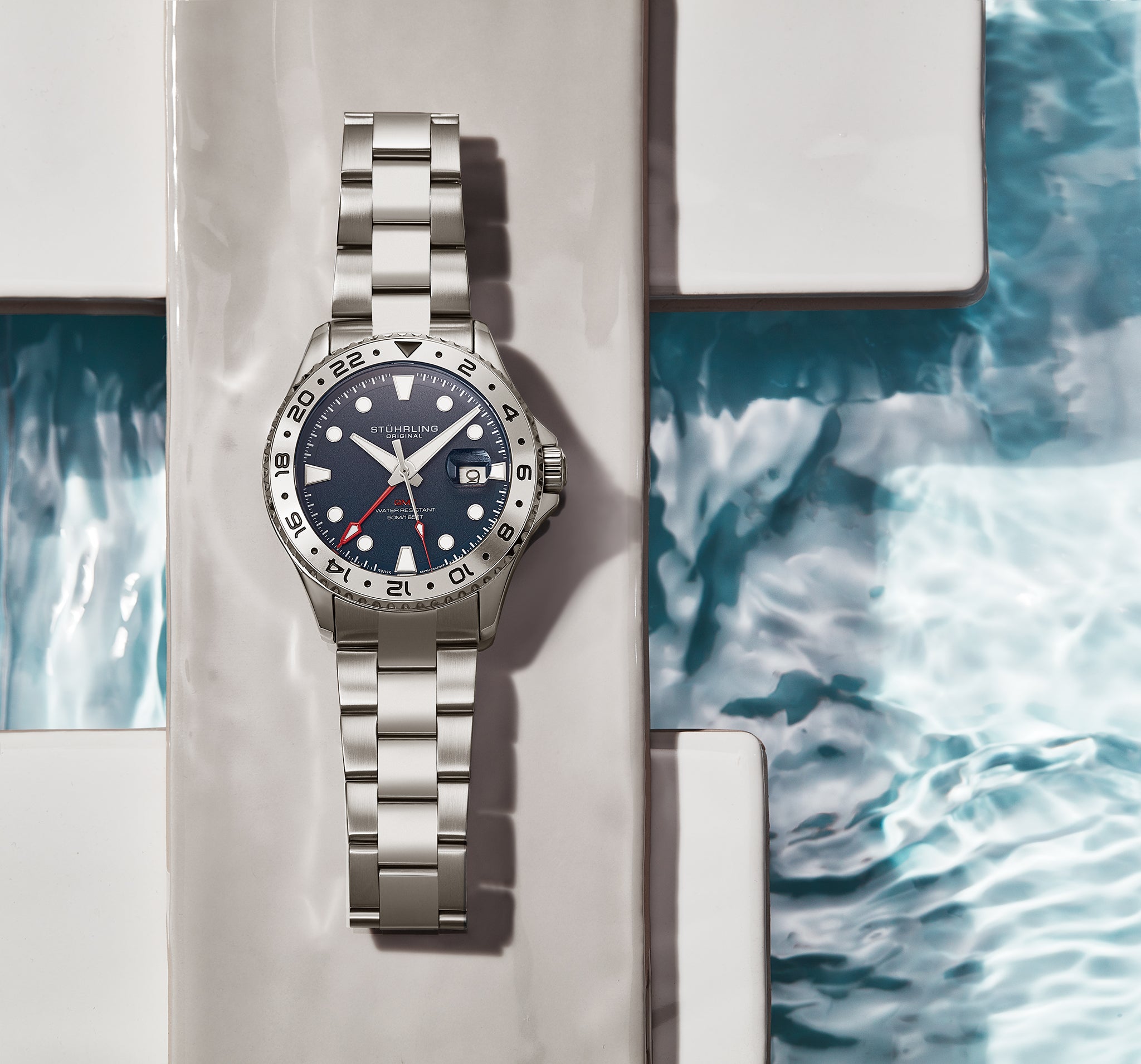 Silver watch with a blue face on a white surface with water pattern